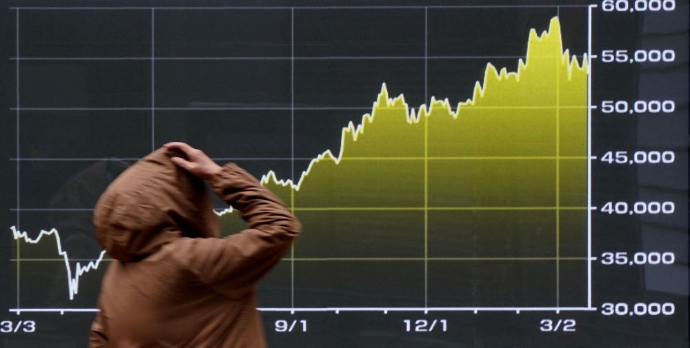 A passerby looks at a graph depicting stock market trends on the Tokyo Stock Exchange. In Asia markets, Japan’s Nikkei index and South Korea’s Kospi were up by more than 3 per cent. — AFP pic