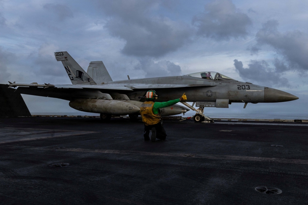 A US Navy sailor prepares to launch an F/A-18E Super Hornet from the flight deck of the Nimitz-class aircraft carrier USS Abraham Lincoln in support of the Operation Epic Fury attack on Iran at an undisclosed location, March 22, 2026. — US Navy/Handout via Reuters