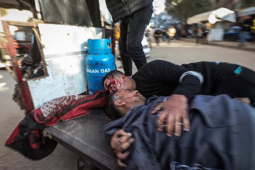 Two men are transported to hospital after a Palestinian police jeep was targeted by a air strike in Nuseirat refugee camp in the central Gaza Strip on March 22, 2026. — AFP pic