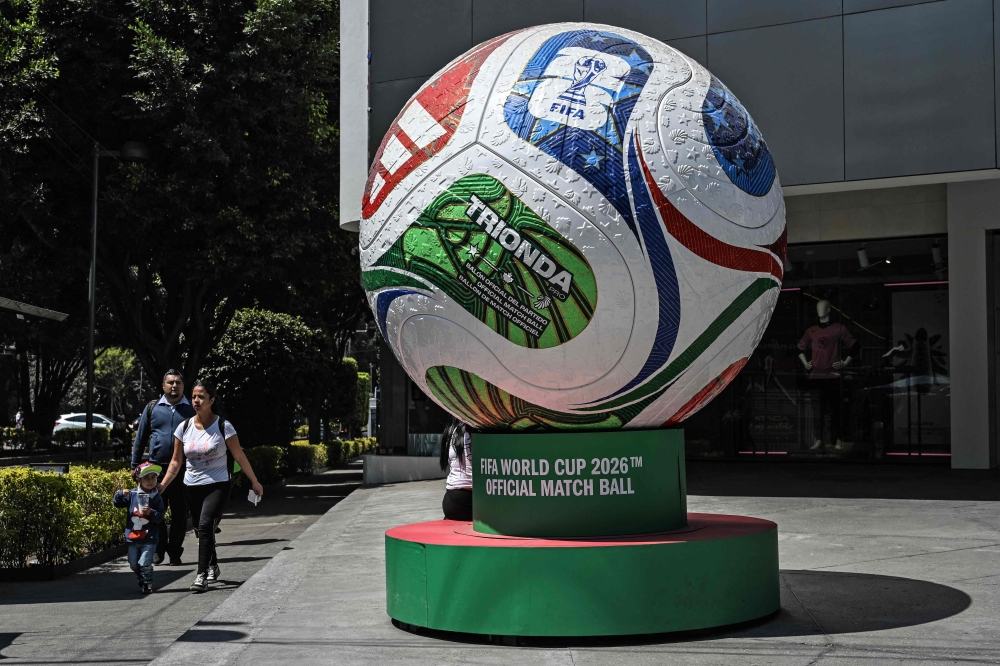 A family walks past a giant model of the official football called ‘Trionda’ in the upscale Polanco neighbourhood as part of the announcements marking 100 days for the 2026 Fifa World Cup, in Mexico City on March 3, 2026. — AFP pic 