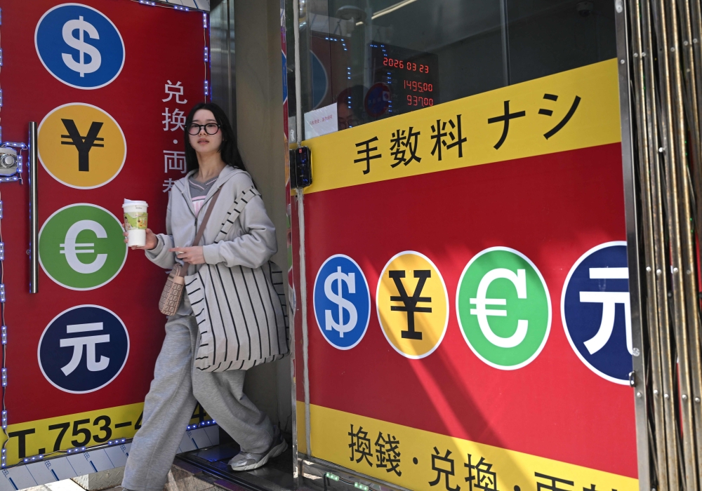 A pedestrian walks past a money exchange sign at a shopping district in Seoul. Currency markets showed signs of fatigue, with traders growing cautious despite ongoing US efforts to end the Iran war. — AFP pic
