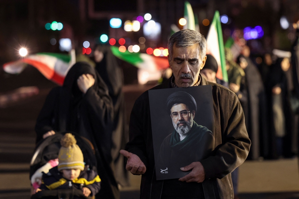 A man reacts as he holds a portrait of Iran’s supreme leader Mojtaba Khamenei as people march in support of the Iranian armed forces in central Tehran March 25, 2026. — AFP pic