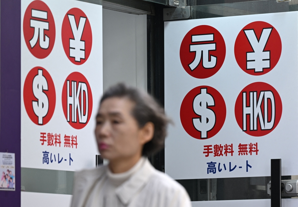 A pedestrian walks past a money exchange sign at a shopping district in Seoul. The ringgit strengthened for a third straight session as markets reacted to potential US-Iran ceasefire talks. — AFP pic