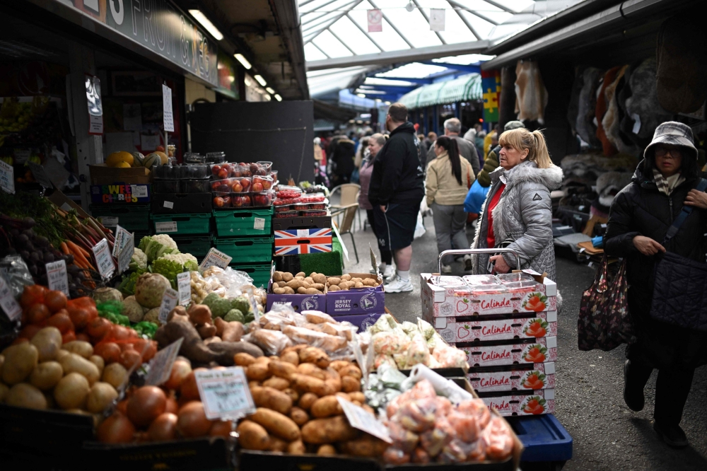 Shoppers make their way around various stalls at Bury Market in Bury, Greater Manchester. UK business groups have urged policymakers to ease cost pressures and shield households from rising living expenses. — AFP pic