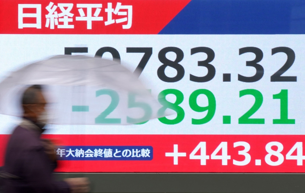 A pedestrian walks past an electronic quotation board displaying the Nikkei Stock Average on the Tokyo Stock Exchange. Asian stocks fell while oil prices surged, reflecting investor caution amid escalating tensions in the Middle East. — AFP pic