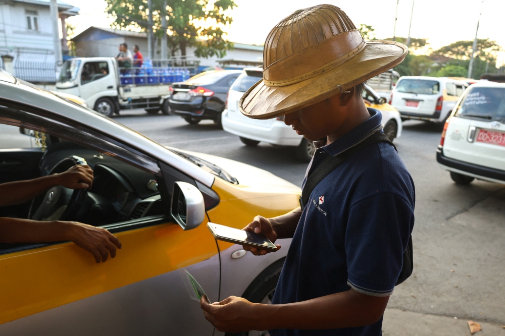 A worker uses a smartphone to scan a QR code to check a vehicle’s eligibility to refuel at a petrol station amid the US-Israeli war on Iran in Yangon, Myanmar on March 20, 2026. — Reuters pic