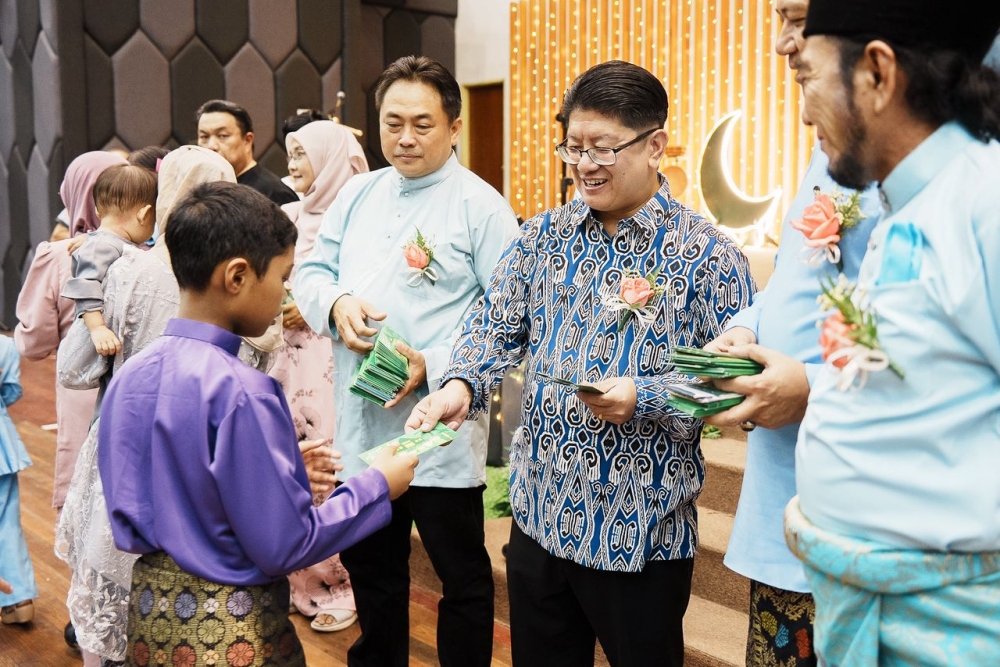 Ewon presents duit raya to children attending the open house at Dewan Sri Putatan. — The Borneo Post pic