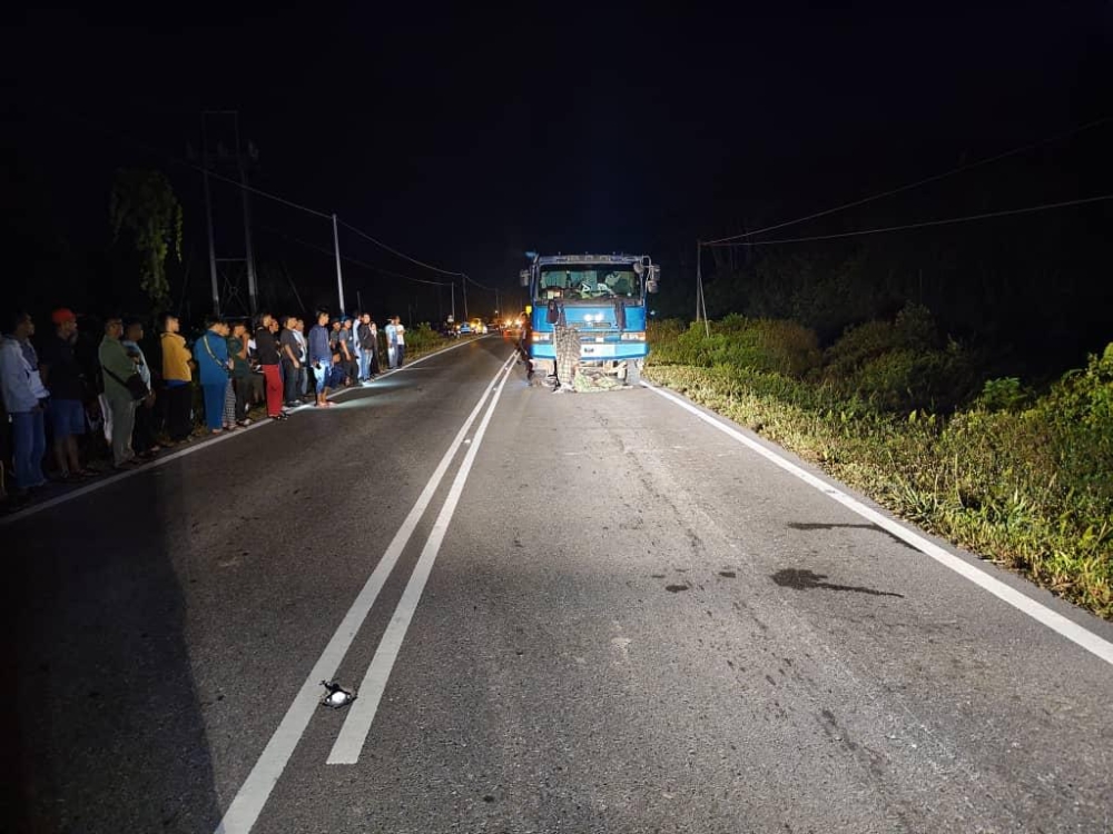 Onlookers observe the scene of the fatal accident. — The Borneo Post pic