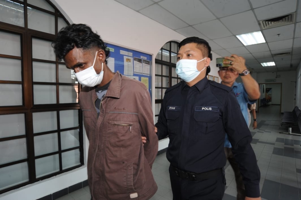 The accused, R. Sivanesan, is escorted by a policeman at the Johor Bahru court complex on March 27, 2026. — Picture by Ben Tan