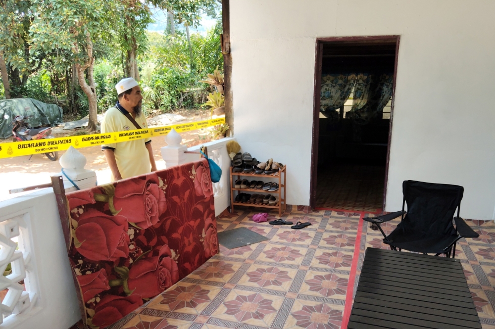 A friend of the family outside a house in Kampung Belau, Merbok, where three people were found dead on March 26, 2026. — Bernama pic