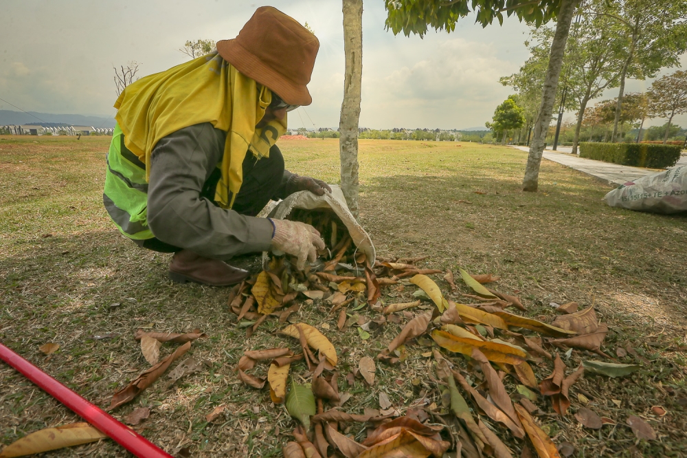 A worker in a public park in Kuala Lumpur is fully covered up as protection from the scorching sun. — Picture by Raymond Manuel