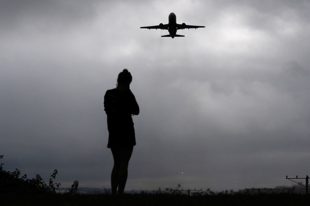 A runner watches as a plane takes off from Reagan Washington National Airport as the US government shutdown continues in Arlington, Virginia October 8, 2025. — Reuters pic