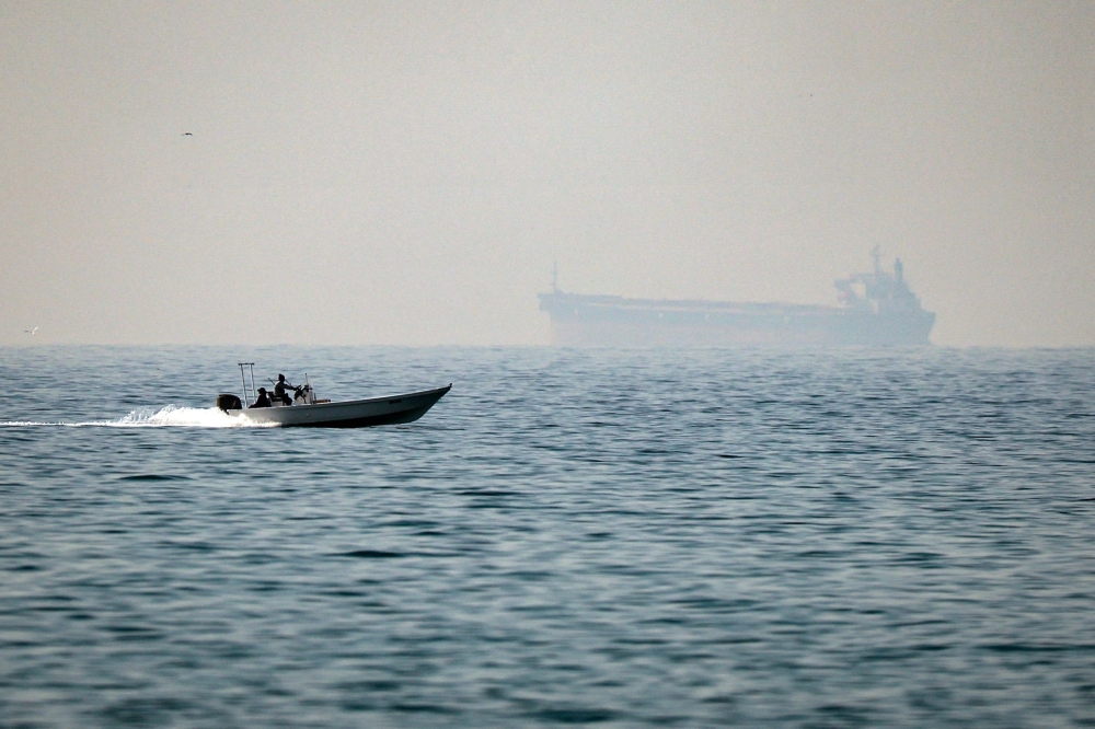 A motorboat cruises along the shore off the town of Al Jeer on the Strait of Hormuz in the northern emirate of Ras Al Khaimah, with a tanker seen in the background, on February 25, 2026.  — AFP pic