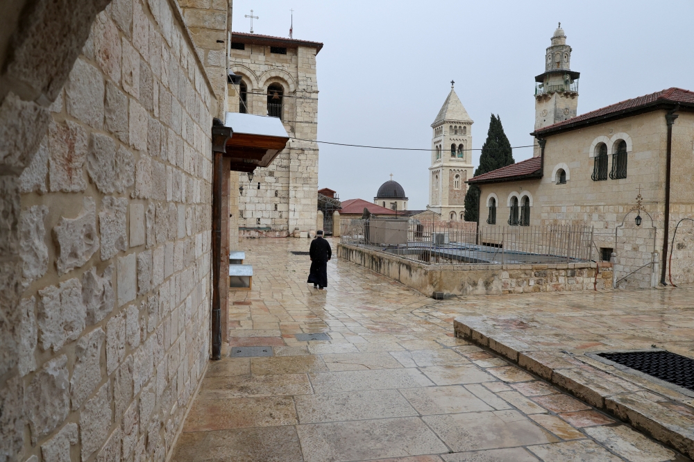 A person walks near the Church of the Holy Sepulchre as it is locked following the cancellation of the traditional Palm Sunday procession from the Mount of Olives, amid restrictions on gathering in large groups and the US-Israel conflict with Iran, in Jerusalem's Old City March 29, 2026. — Reuters pic