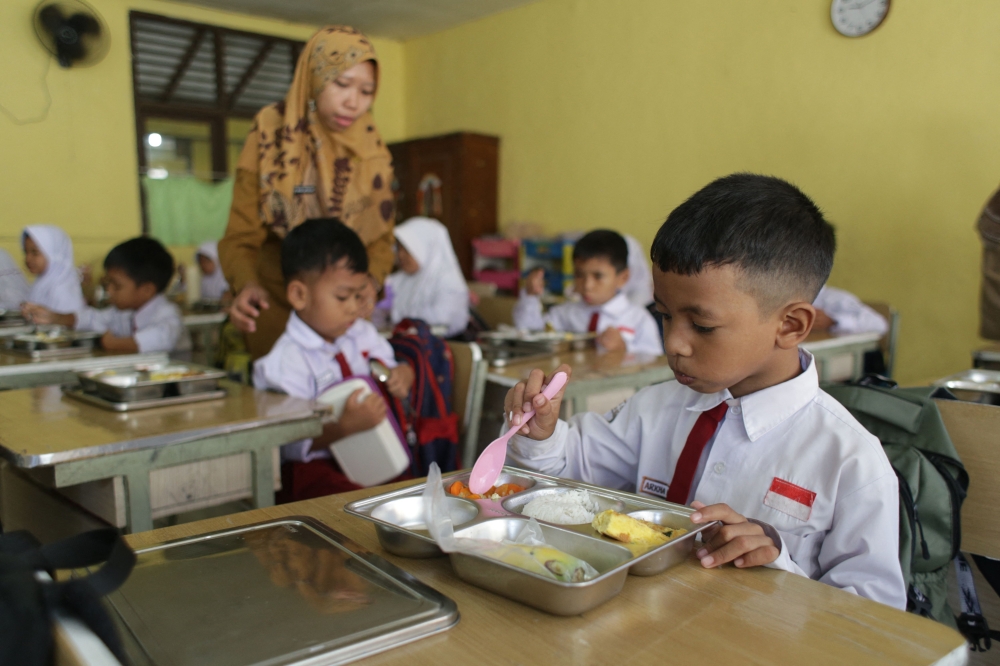Students eat their lunch on the first day of a free-meal programme at Kedung Badag 1 State Elementary School in Bogor, West Java, on January 6, 2025. Indonesia is looking to save up to 40 trillion rupiah (RM9 billion) by cutting back on its free meal programme, an official told AFP today. — AFP pic 