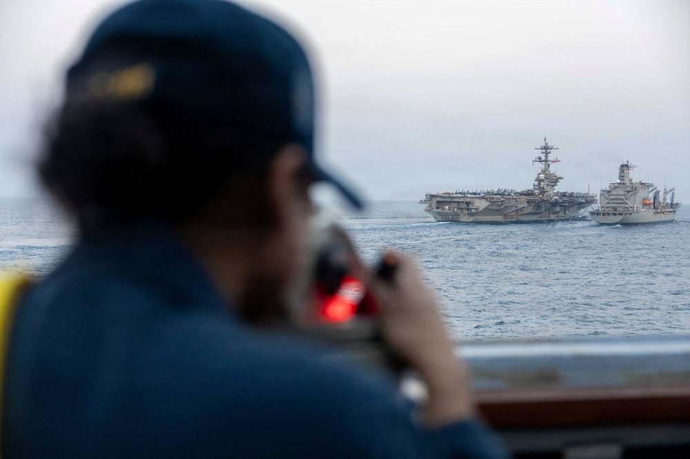 A US Navy sailor looks out as Nimitz-class aircraft carrier USS Abraham Lincoln conducts a replenishment-at-sea with fleet replenishment oiler USNS Henry J. Kaiser during the Operation Epic Fury attack on Iran at an undisclosed location, March 18, 2026. Iran’s navy chief Shahram Irani said today that the USS Abraham Lincoln aircraft carrier would be targeted by the Islamic republic if it comes within range. — US Navy handout pic via Reuters