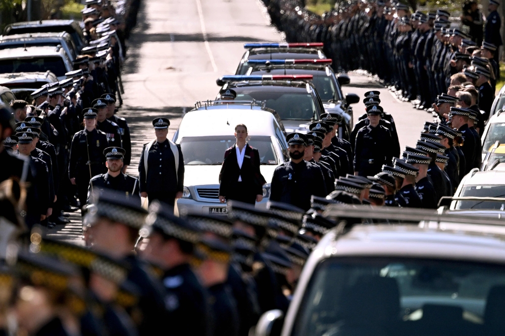 A police guard of honour salutes as the coffin of Senior Constable Vadim de Waart-Hottart, one of two officers shot dead by a fugitive gunman, is transported in a funeral procession in Melbourne on September 5, 2025. Australian police said today they shot dead a fugitive gunman wanted for killing two officers, ending a seven-month manhunt for one of the country’s most-wanted criminals. — AFP pic 