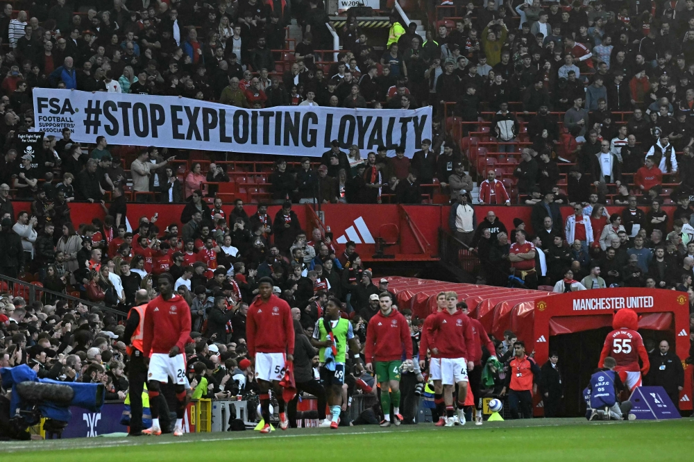 United fans, many wearing black as a protest, display a banner in the crowd against seat prices and the current ownership of Manchester United ahead of the English Premier League football match between Manchester United and Arsenal at Old Trafford in Manchester March 9, 2025. — AFP pic 