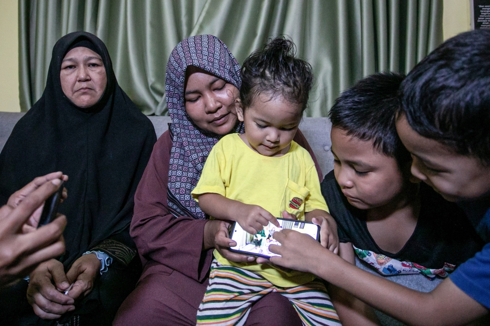 Widow Nor Nadia Abdul Majid (second from left), 32, with her children Muhammad Aqif Amsyar, 9, Muhammad Atif Izz Rayqal, 7, and Nur Humaira, 2, and the late Amirul Hafiz Omar’s mother Faridah Ahmad, 56, look at his photograph at Kampung Repoh, Batu Kurau. — Bernama pic