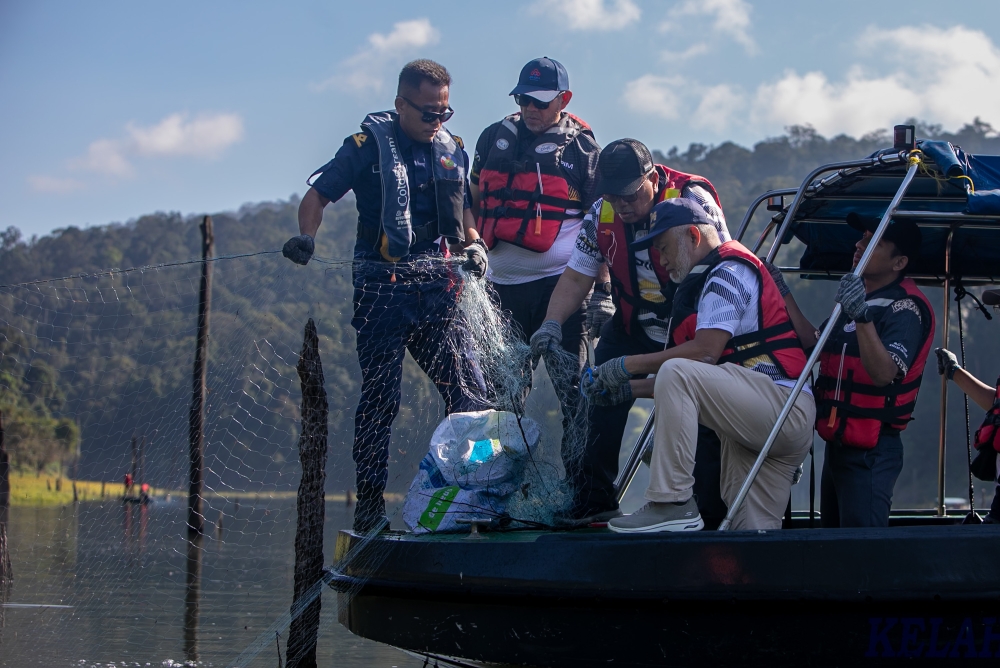 Perak Rural Development, Plantation, Agriculture and Food Industry Committee chairman Datuk Mohd Zolkafly Harun (third left) and Perak Fisheries director Mohd Ghazali Abdul Manap (fourth left) join enforcement officers in clearing abandoned fishing nets at Tasik Temenggor, Gerik, March 31, 2026. — Bernama pic