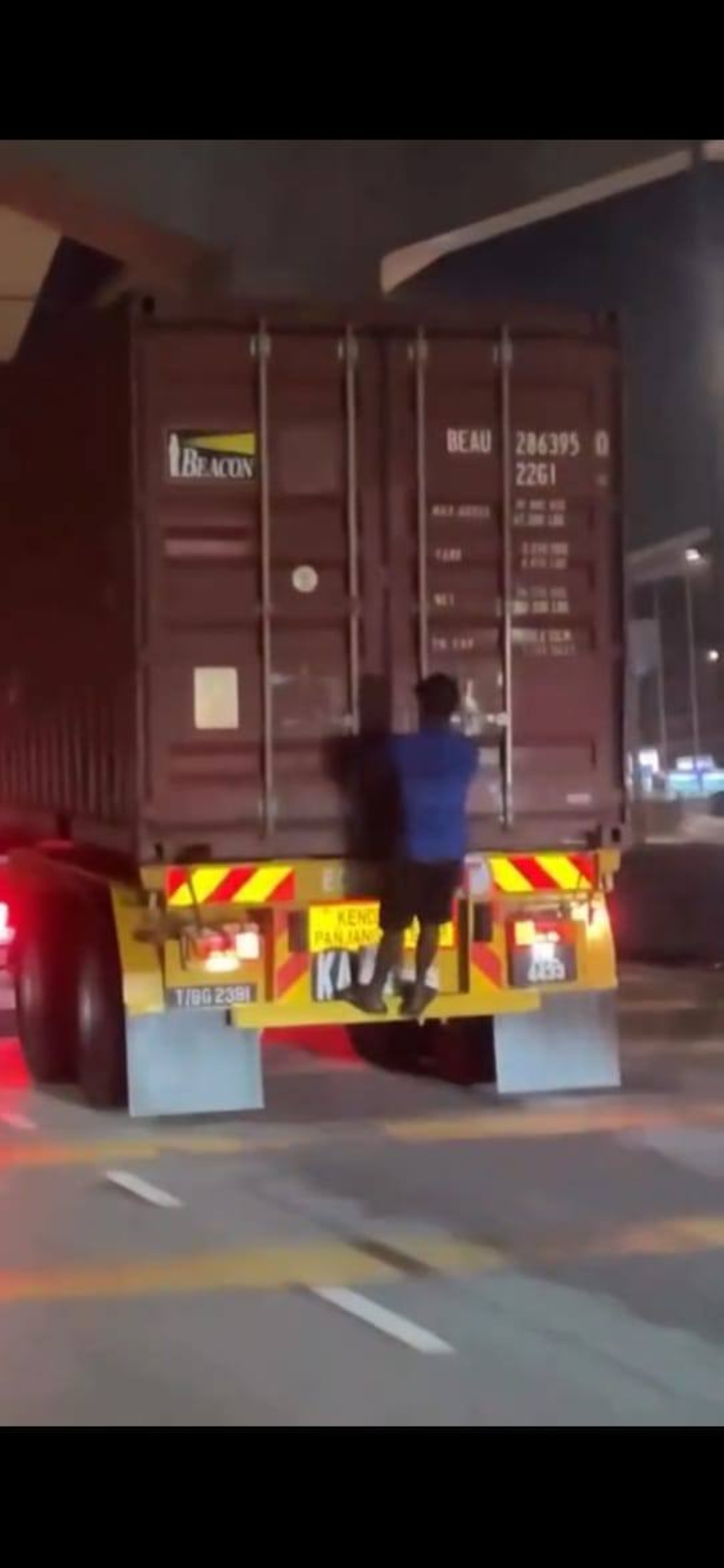 A reckless stunt caught on video has gone viral after a man was seen clinging to the back of a moving trailer truck along Persiaran Tengku Ampuan Rahimah in Klang. — Picture courtesy of police