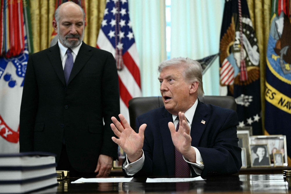 US President Donald Trump speaks as Commerce Secretary Howard Lutnick (L) looks on after he signed an executive order in the Oval Office of the White House in Washington, DC, on March 31, 2026. — AFP pic