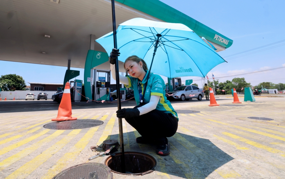 A worker at the Petronas petrol station on Jalan Lintas Kepayan, Athirah Abdul Kahar in Kota Kinabalu measures the amount of petrol supply at the station, March 27, 2026. — Bernama pic 