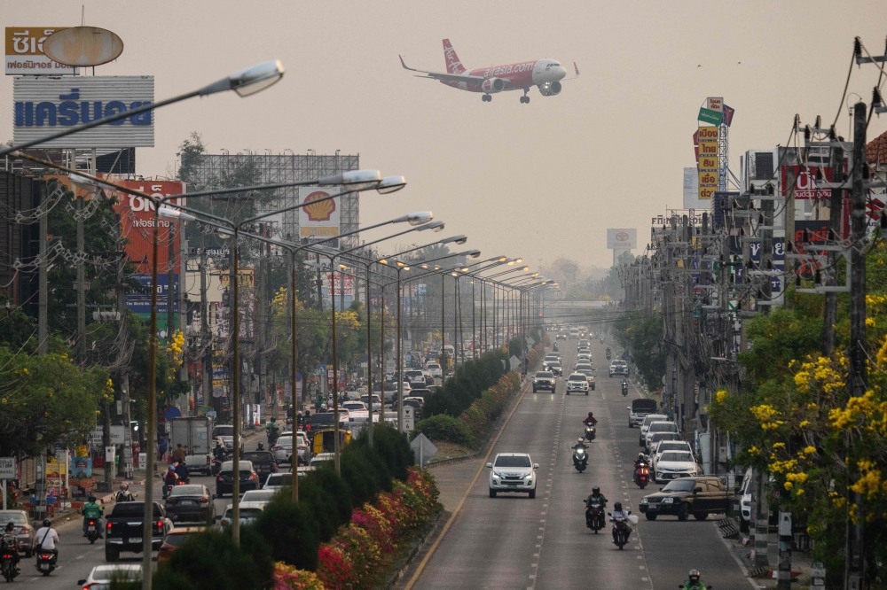 A passenger plane prepares to land at the airport as commuters drive on the road below on a heavily polluted day in Chiang Mai April 2, 2026. — AFP pic
