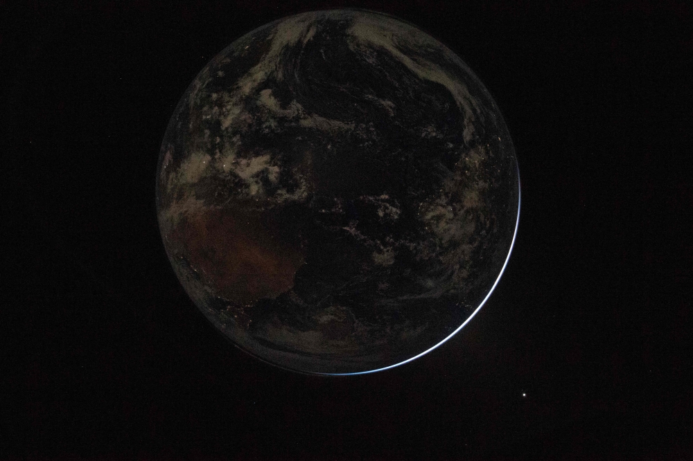 This handout picture provided by Nasa shows a view of a backlit Earth as seen through the Orion spacecraft’s window, photographed by Nasa astronaut Reid Wiseman, commander of Artemis II, on April 2, 2026, after completing the translunar injection burn. — AFP pic/Nasa