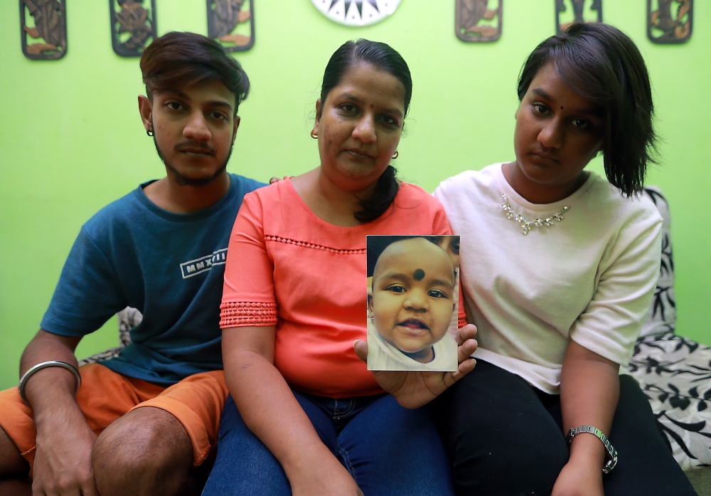 Indira, holding a photograph of Prasana Diksa, being comforted by her two other children Tevi Darsiny (left) and Karan Dinish. — File picture by Farhan Najib 