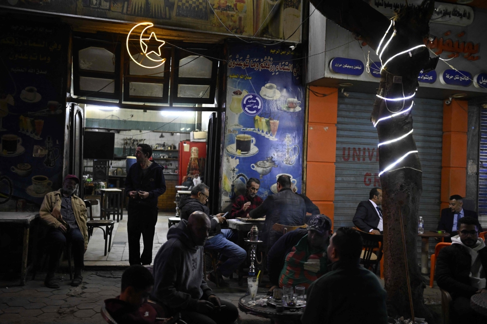 People play a game of dominos as they sit at a roadside cafe before closing in downtown Cairo on April 2, 2026. — AFP pic