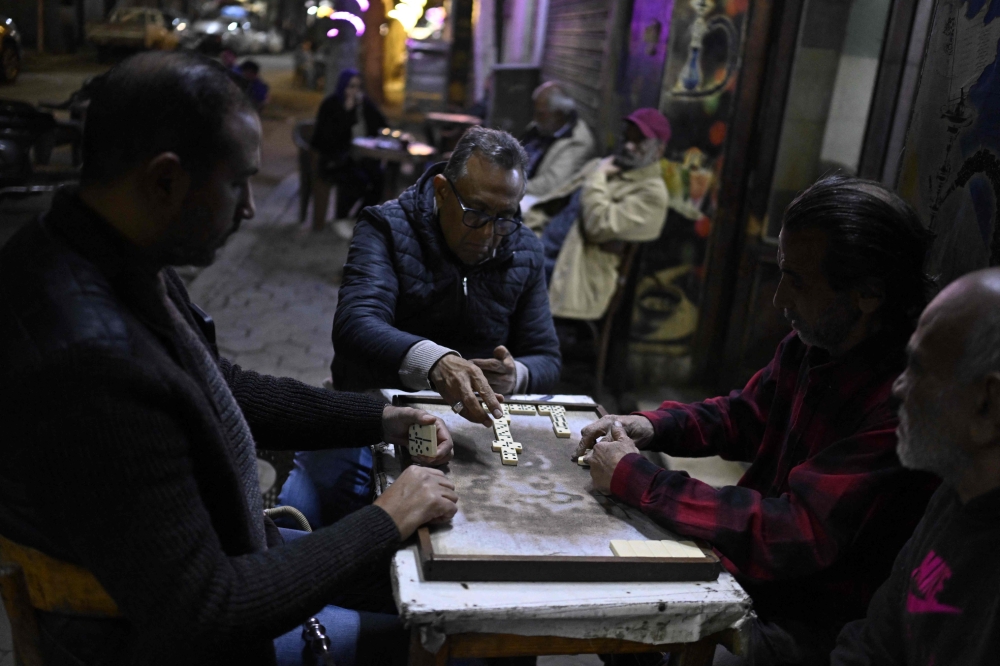 People play a game of dominos as they sit at a roadside cafe before closing in downtown Cairo on April 2, 2026. — AFP pic