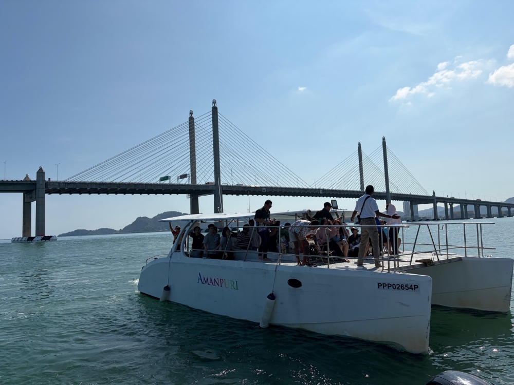 Visitors take a boat tour offering scenic views of the Second Penang Bridge. — Picture by Opalyn Mok