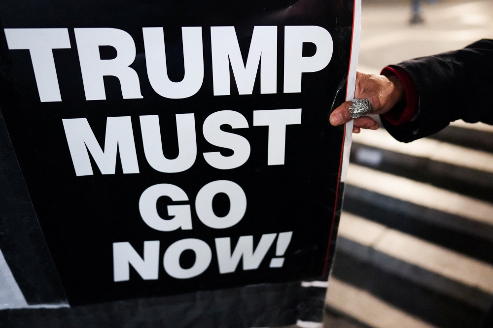 A person holds a sign that reads, “Trump Must Go Now!”, during a protest against the US-Israeli conflict with Iran in New York City on April 7, 2026. — Reuters pic