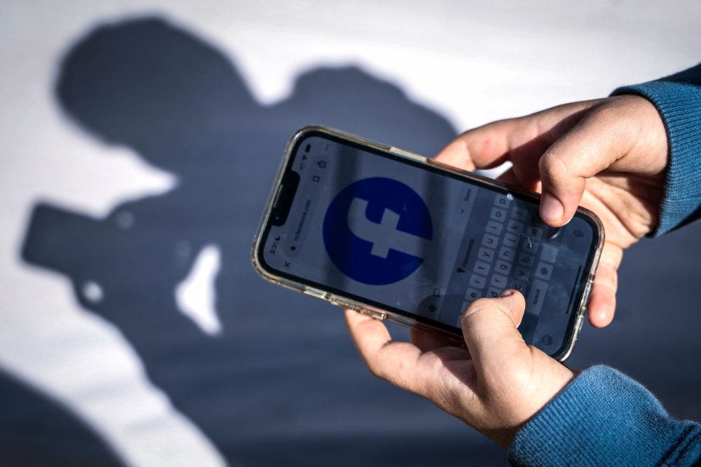 A person looks at social media on a mobile phone on October 24, 2025. — AFP pic