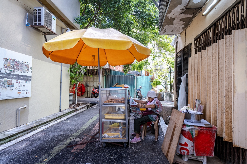 Wong passes the time by reading a newspaper or inspecting the day’s batch of pastries while waiting for customers. — Picture by Firdaus Latif