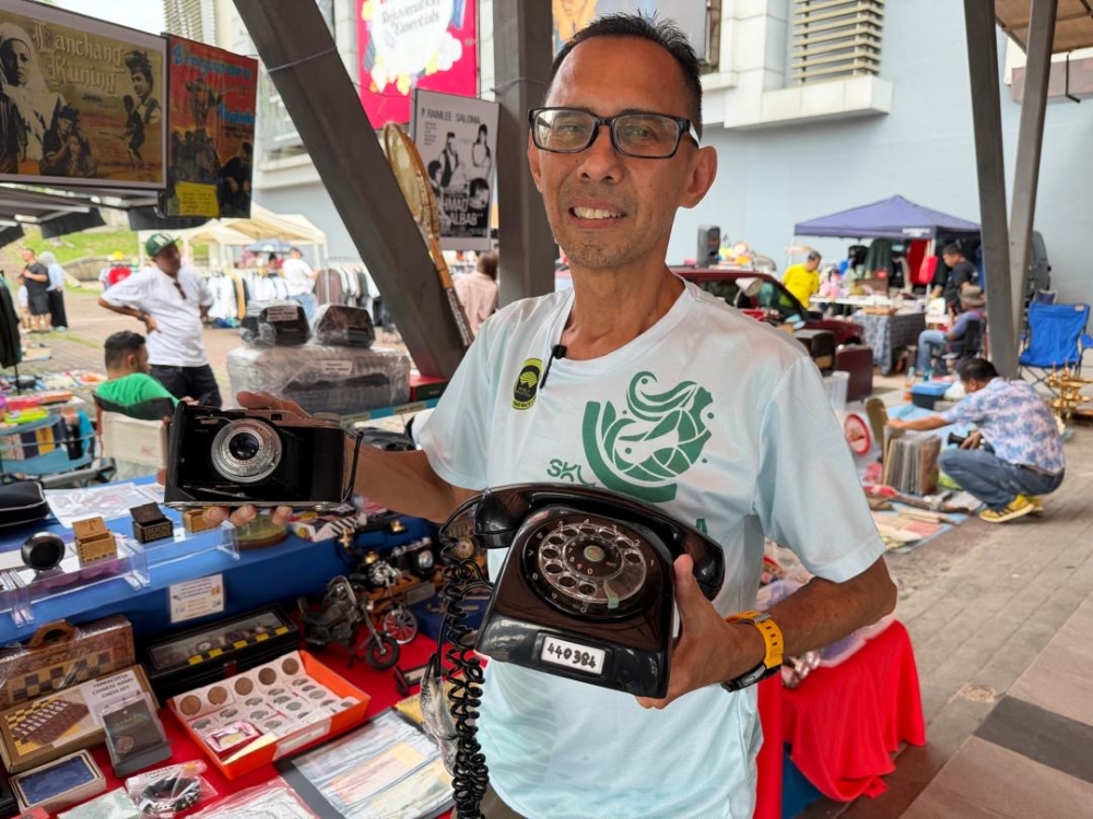 Pasar Pagi vendor Syed Fadzlon Syed Ahmad Al Edrus with his personal collection, including a vintage Ericsson rotary house phone and a classic German-made Ansco Viking folding camera from the 1950s. — Picture by Ben Tan