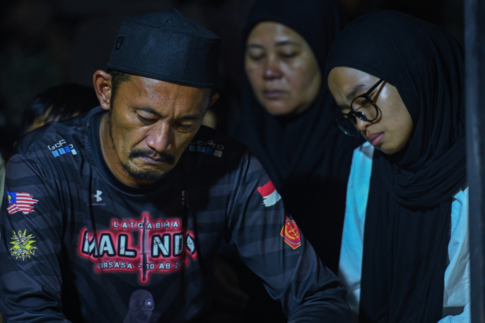 Rosafindi Tambi Chik (left), father of the late Private Muhammad Amirul Raziq, appears visibly distraught after completing his son’s burial at the Felda Sungai Kelamah Cemetery in Gemas on April 11, 2026. — Bernama pic