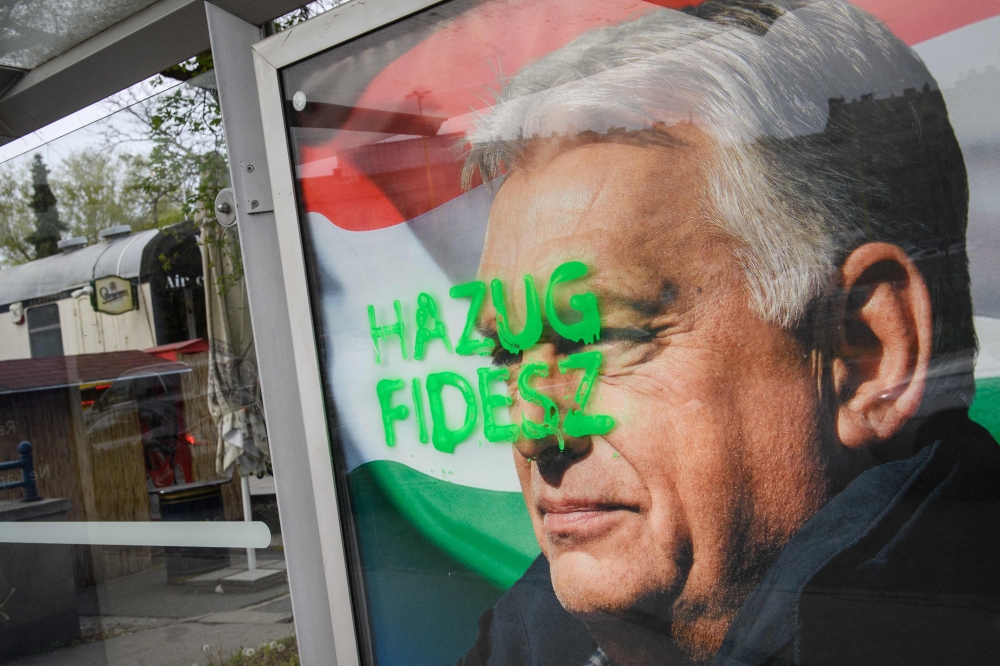 A tag reading “Liar Fidesz” is seen over a placard showing outgoing Hungarian Prime Minister Viktor Orban at a bus stop near the South Railway Station in Budapest on April 13, 2026. — AFP pic