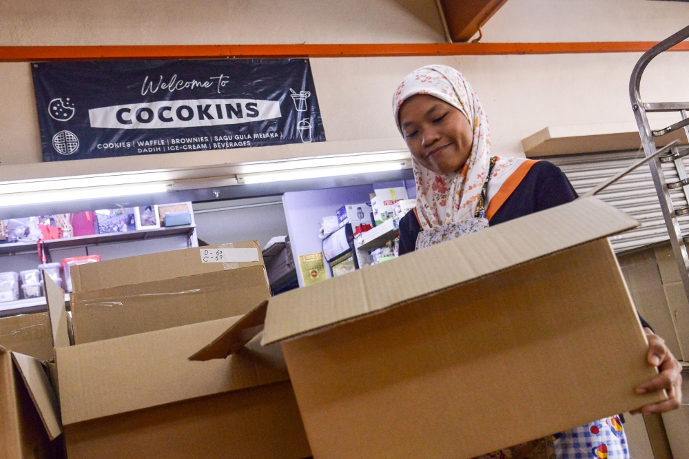 Nurul Asyiqin packs cookie capsules into boxes to be sent to regular customers from the private and public sectors who have ordered her products. — Bernama pic