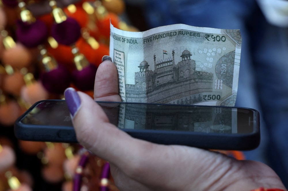 A woman holds a five-hundred-rupee currency note in the old quarters of Delhi, India on September 25, 2025. — Reuters pic