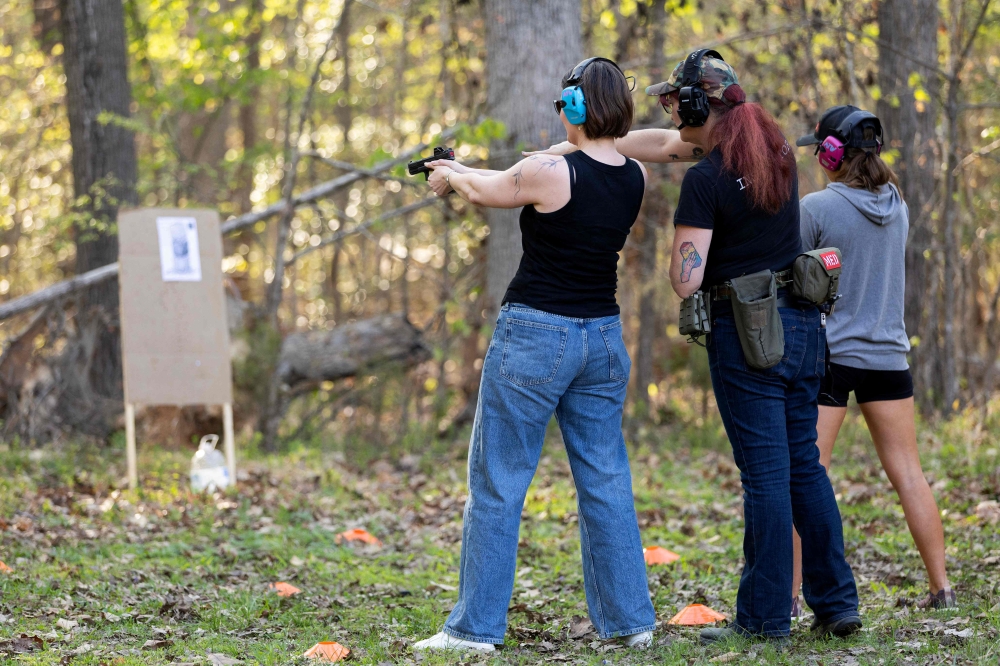 A student (left) prepares to shoot as Clara Elliott (centre) instructs proper technique during an introductory firearms class at a backyard shooting range in Midlothian, Virginia, April 11, 2026. — AFP pic