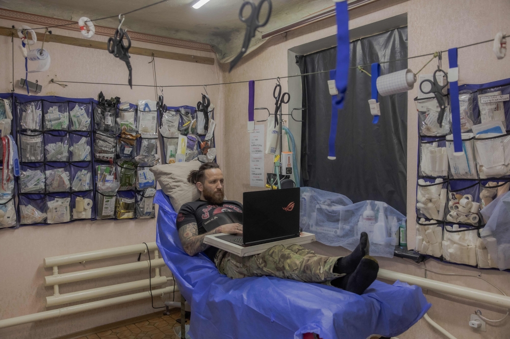 Ukrainian combat medic Mykola Yasinenko uses his laptop at a stabilisation point of the 56th brigade, where he serves, in the eastern Donetsk region, on March 15, 2026, amid the Russian invasion of Ukraine. — AFP pic