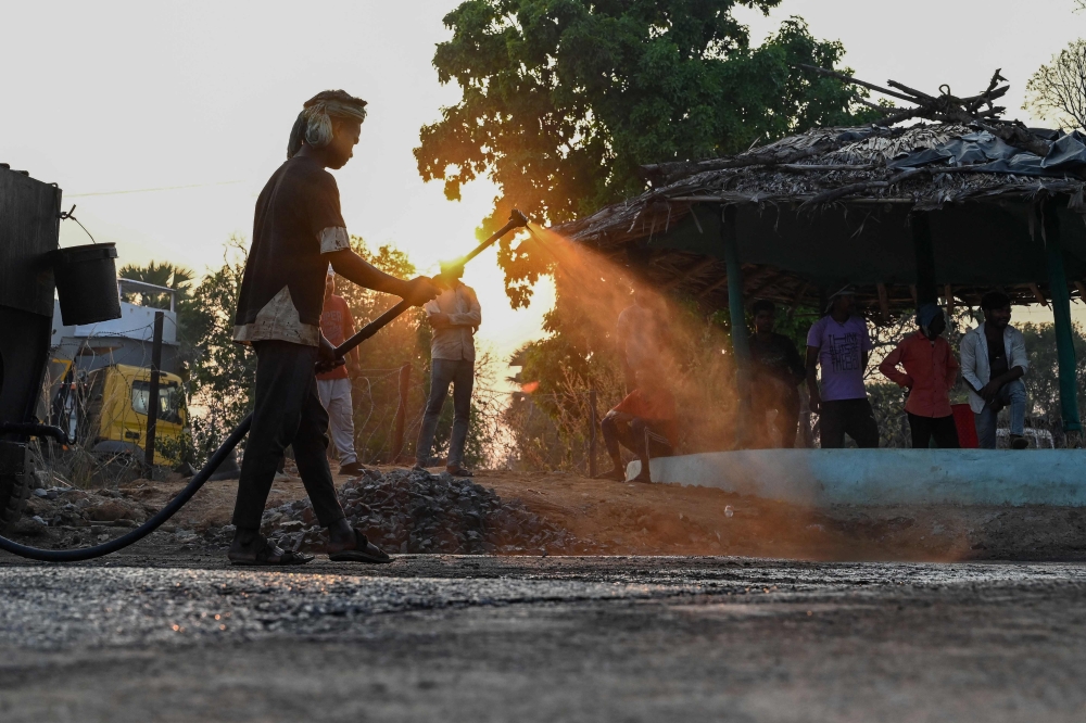 A Border Roads Organisation worker sprays down billows of red dust during road construction in Bijapur, Chhattisgarh state, India on March 31, 2026, opening the former fortresses of Maoist rebels to the mining industry. — AFP pic