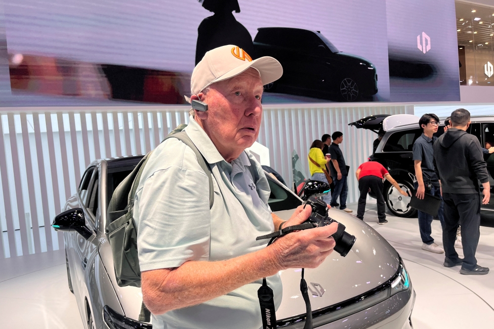 New Zealand retiree John Cordell holds a camera as he visits the Leapmotor booth during a tour by American YouTuber Ethan Robertson at the Beijing International Automotive Exhibition, or Auto China, in Beijing April 26, 2026. — Reuters pic