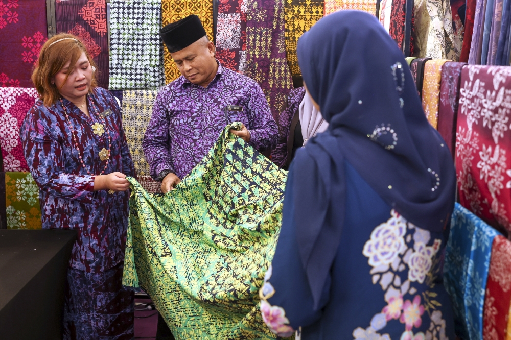 Kraftangan Malaysia Pahang branch director Juhari Azmi (second left) views batik on sale during a visit to the Festival Kraf Pantai Timur 2026 booth at East Coast Mall in Kuantan, Pahang. — Bernama pic