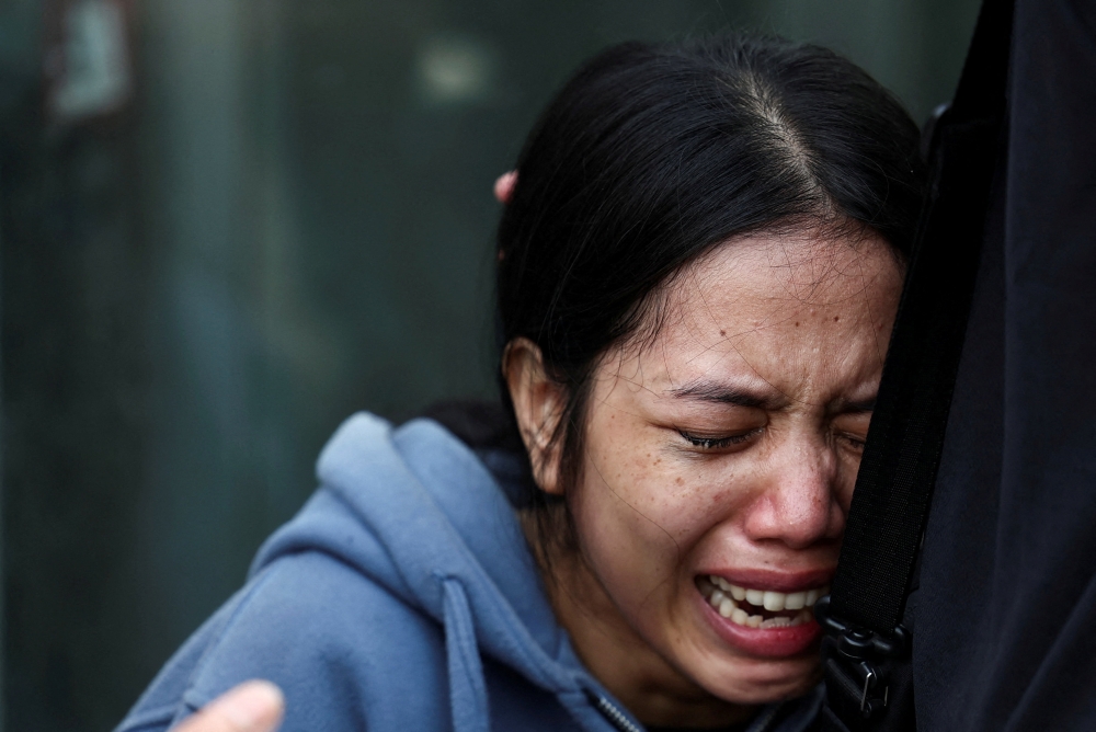 A woman reacts as she waits for an update on her sister outside the station following a deadly collision between a commuter line train and a long-distance train in Bekasi on April 28, 2026. — Reuters pic
