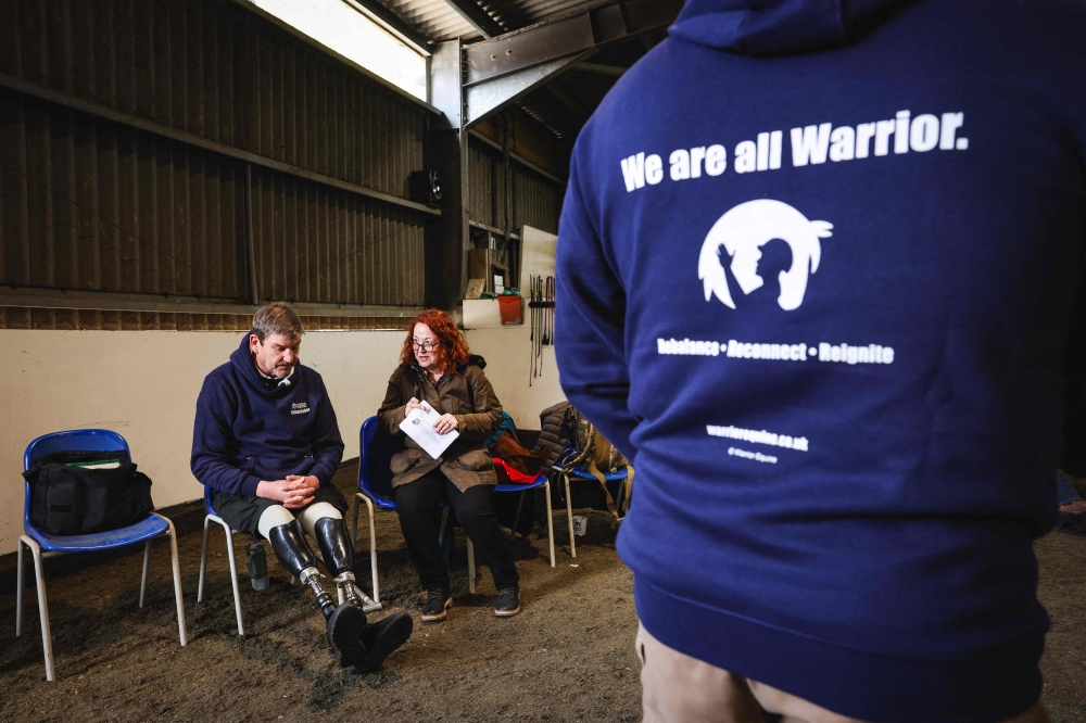 Army veteran Al Strudwick (left), a former Sergeant who served with the Intelligence Corps of the Army, waits his turn to take part in an exercise to gain the trust of a horse at The Light Cavalry Honorable Artillery Company stables near Windsor, west of London. — AFP pic