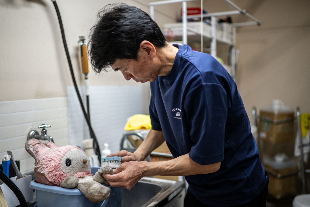 Masakazu Shimura brushes a soft toy during the cleaning process. — AFP pic 