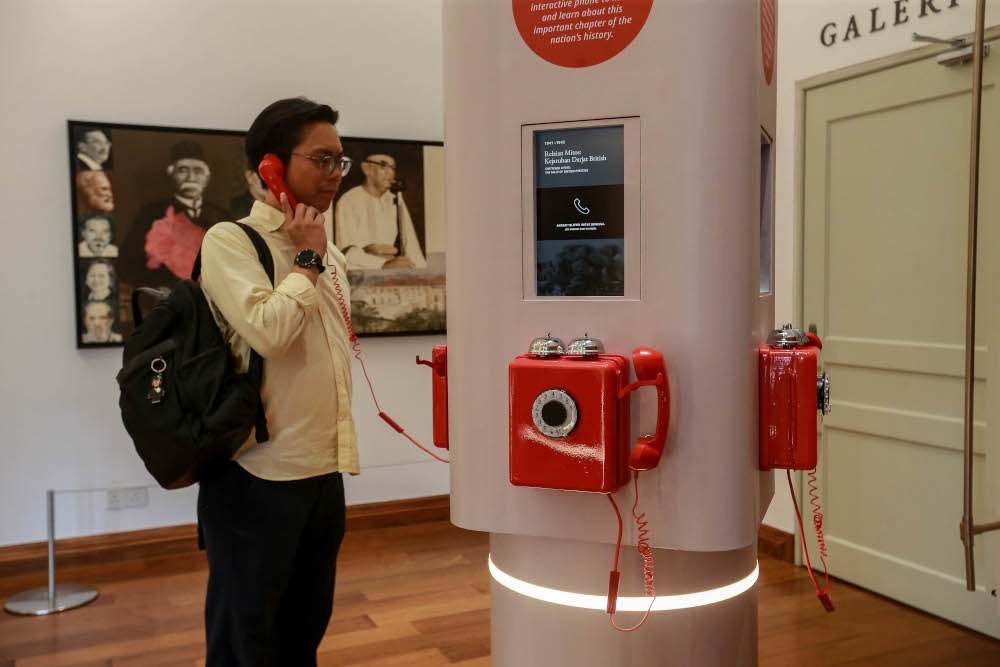 A visitor trying an interactive phone booth that narrates the story of Malaysia’s birth and modernisation journey. — Picture by Sayuti Zainudin 